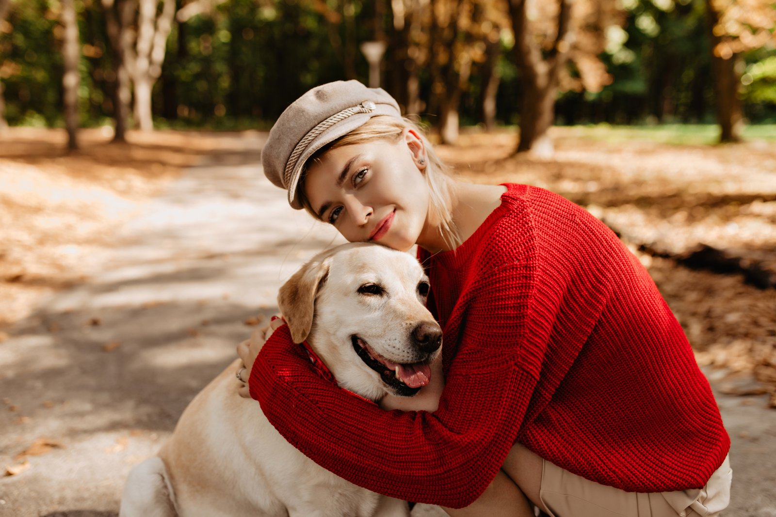 Lovely young woman in nice light hat and red sweater sitting wit